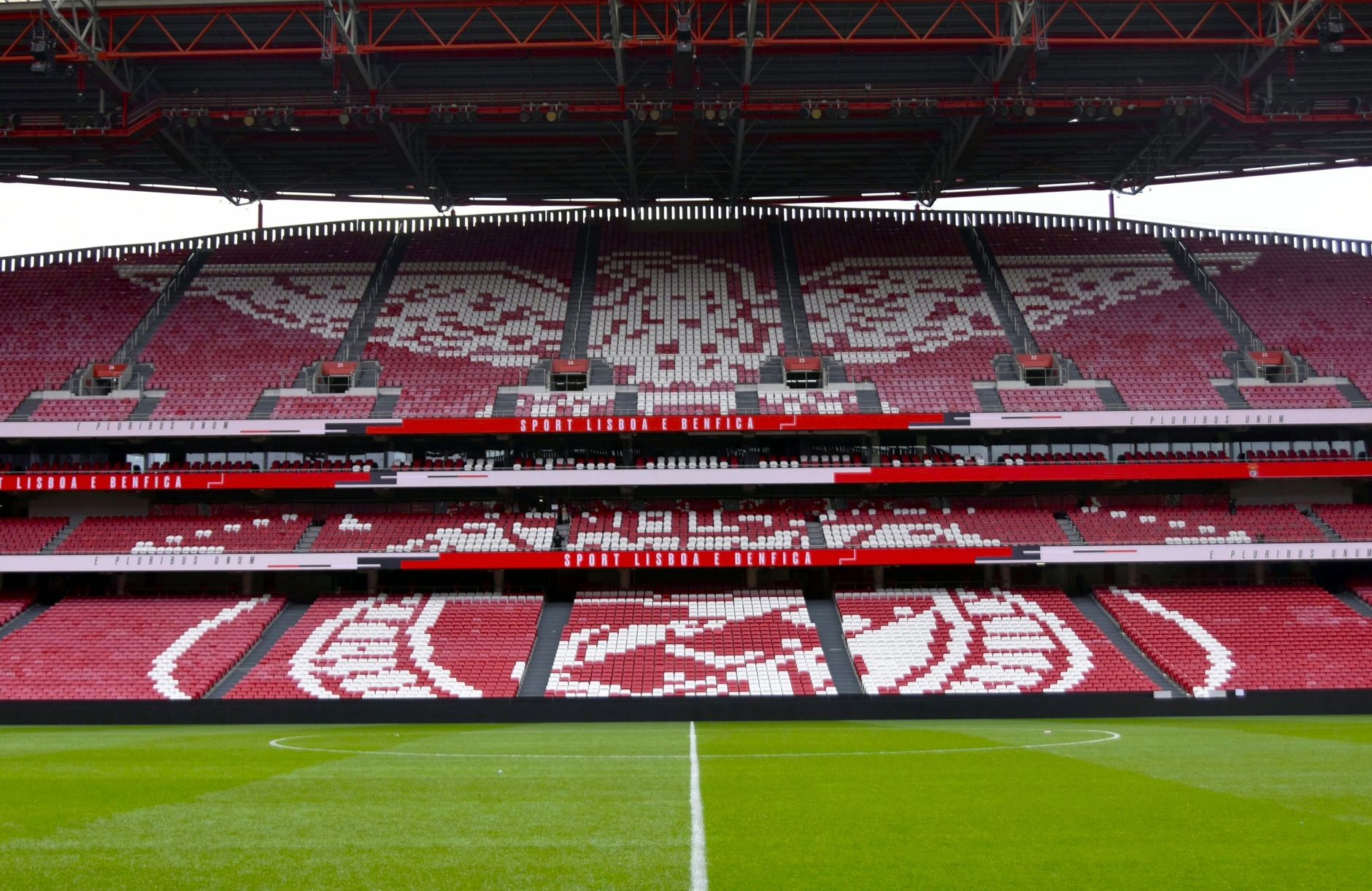 Wide-angle view of the iconic Estádio da Luz stadium in Lisbon, Portugal, showcasing its red seating and field.