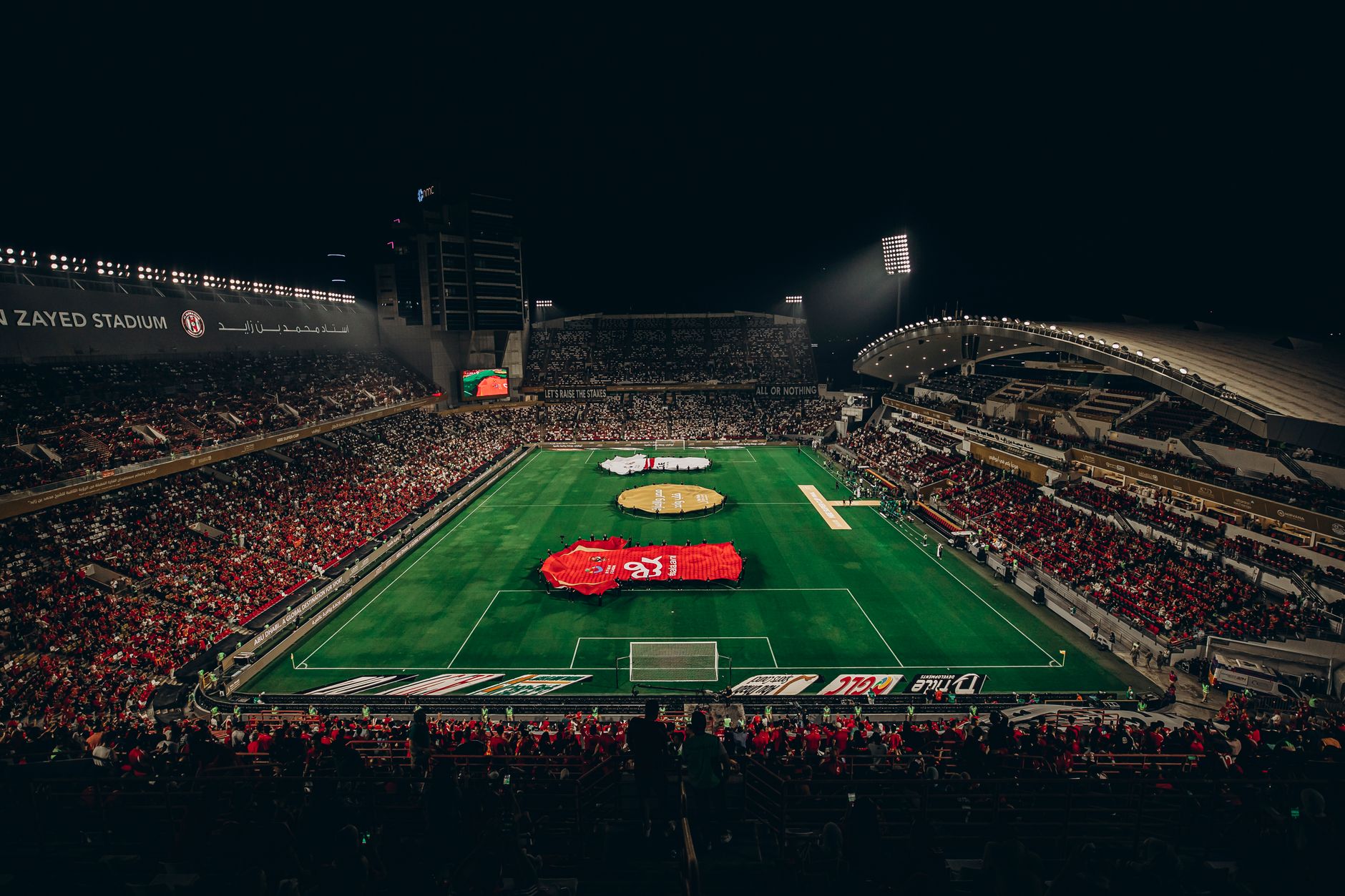 Aerial view of a lively football match at Zayed Stadium, showcasing fans and vibrant atmosphere.