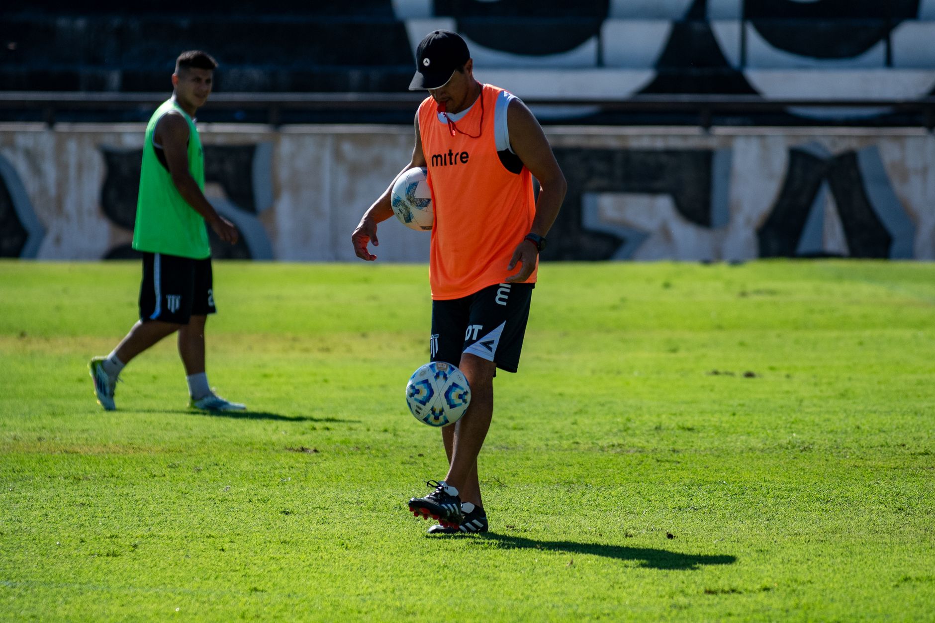 Two soccer players practicing with a ball during a sunny training session on grass field.