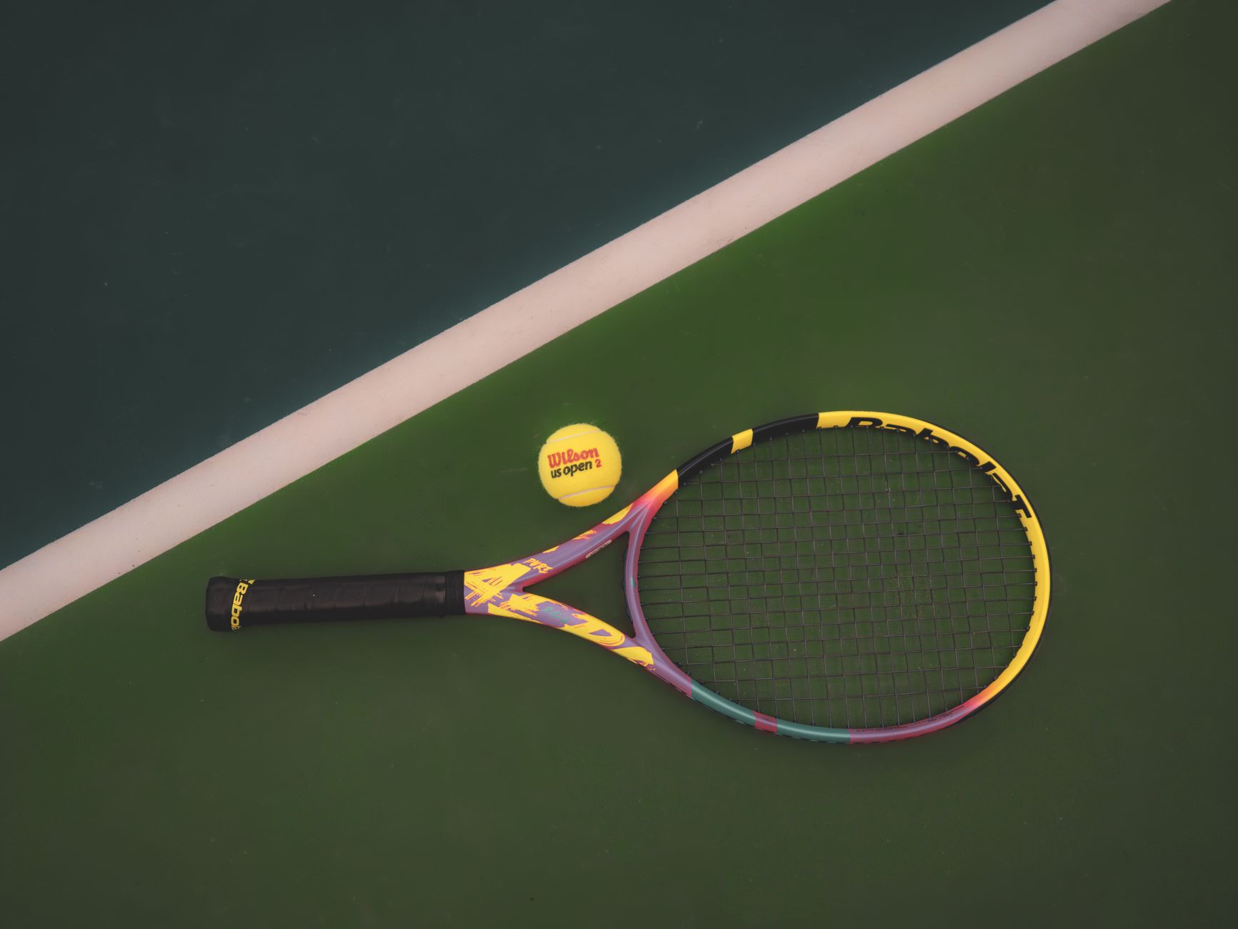 Tennis racket and ball on a vibrant green court, ready for a match.