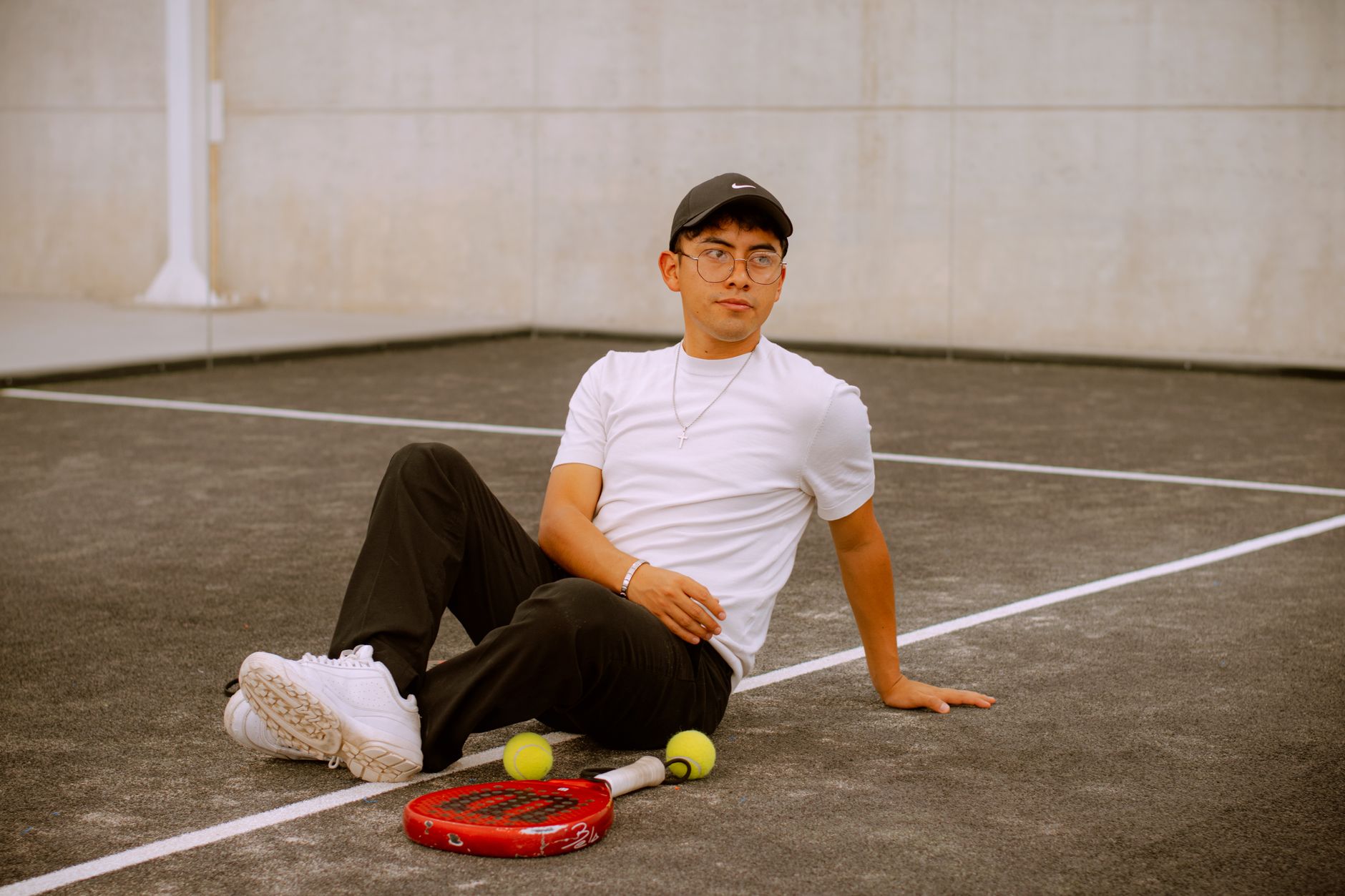Young man in casual attire relaxing on a padel court in Puebla, Mexico.