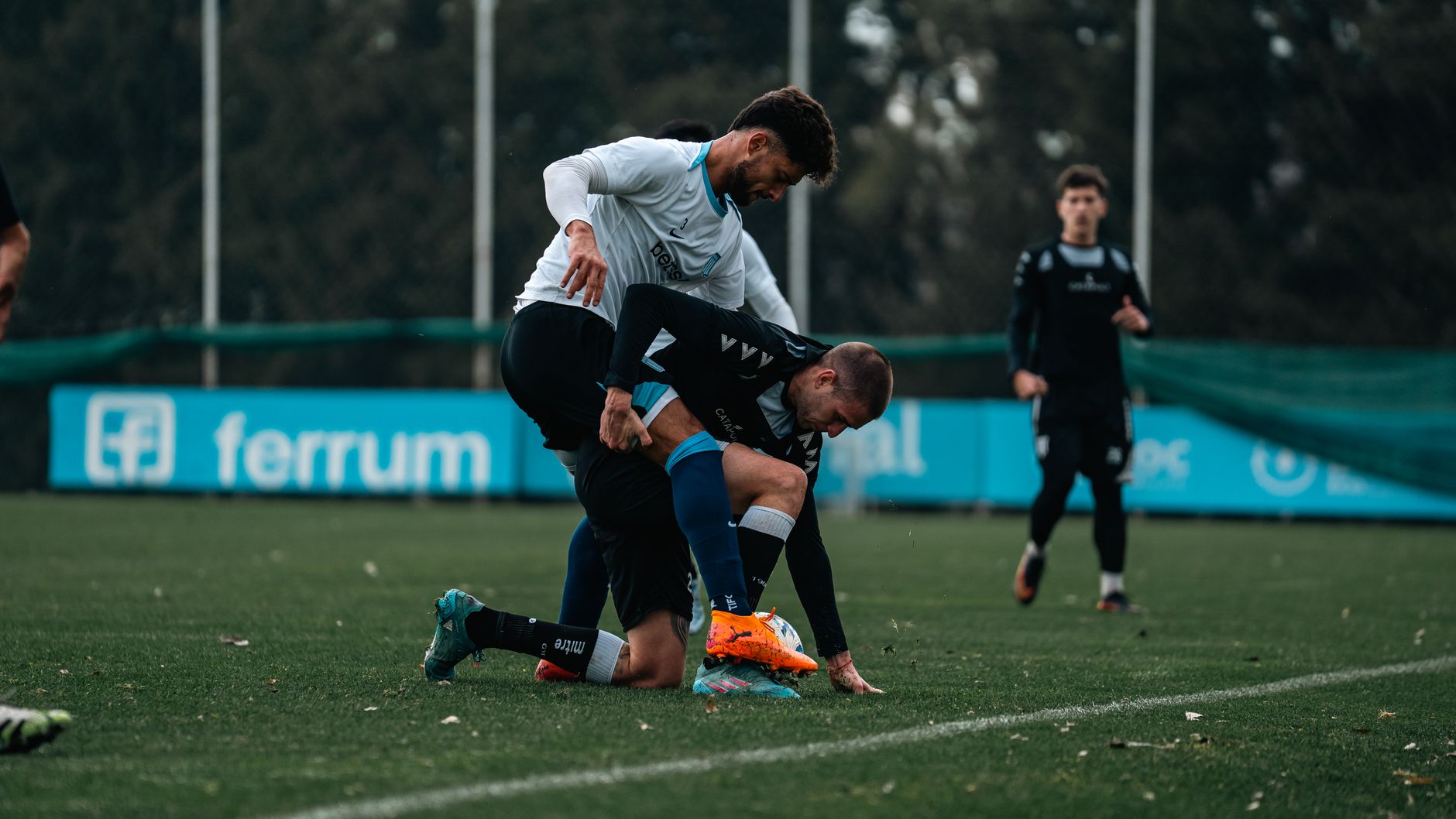 Footballers engaged in an intense match on a grassy outdoor field during the day.