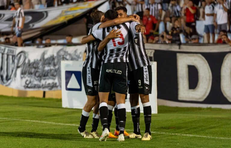 Soccer players in a joyous group hug after scoring a goal, showcasing teamwork and celebration.
