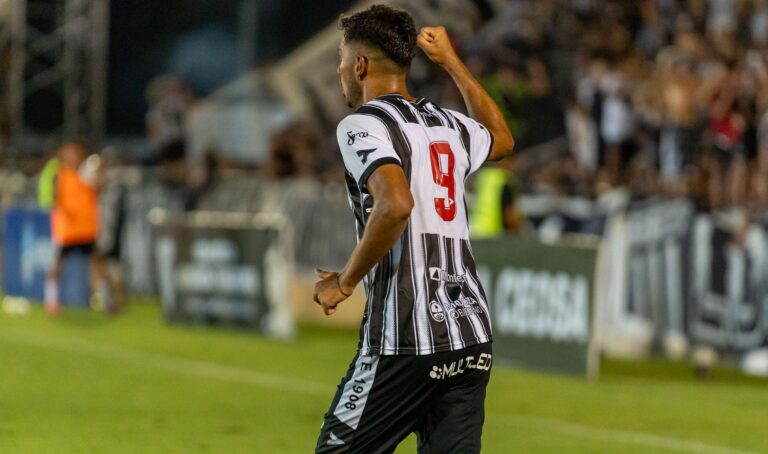 Football player in black-and-white jersey celebrates goal on field.