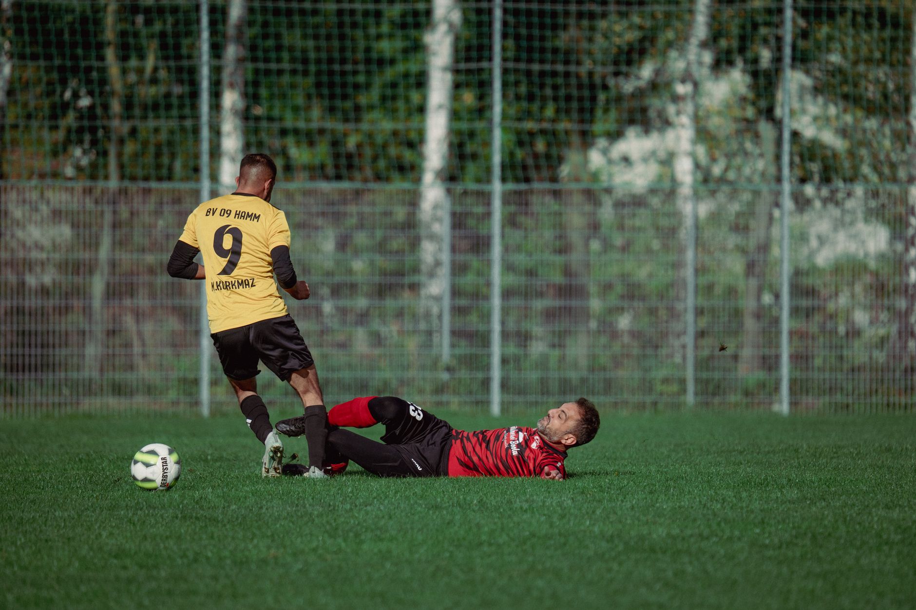 Two soccer players in action with a dramatic tackle on a grassy field during a match.