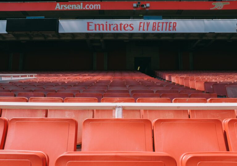Empty red seats at Arsenal's Emirates Stadium in London, showcasing its vibrant atmosphere.