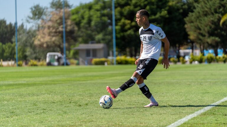 Young male soccer player in action on a sunny outdoor field wearing team uniform.
