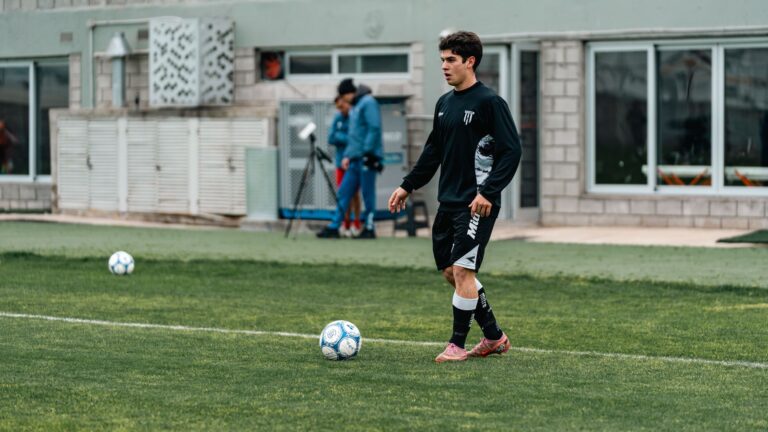 A young soccer player in training gear practices on a grassy field.