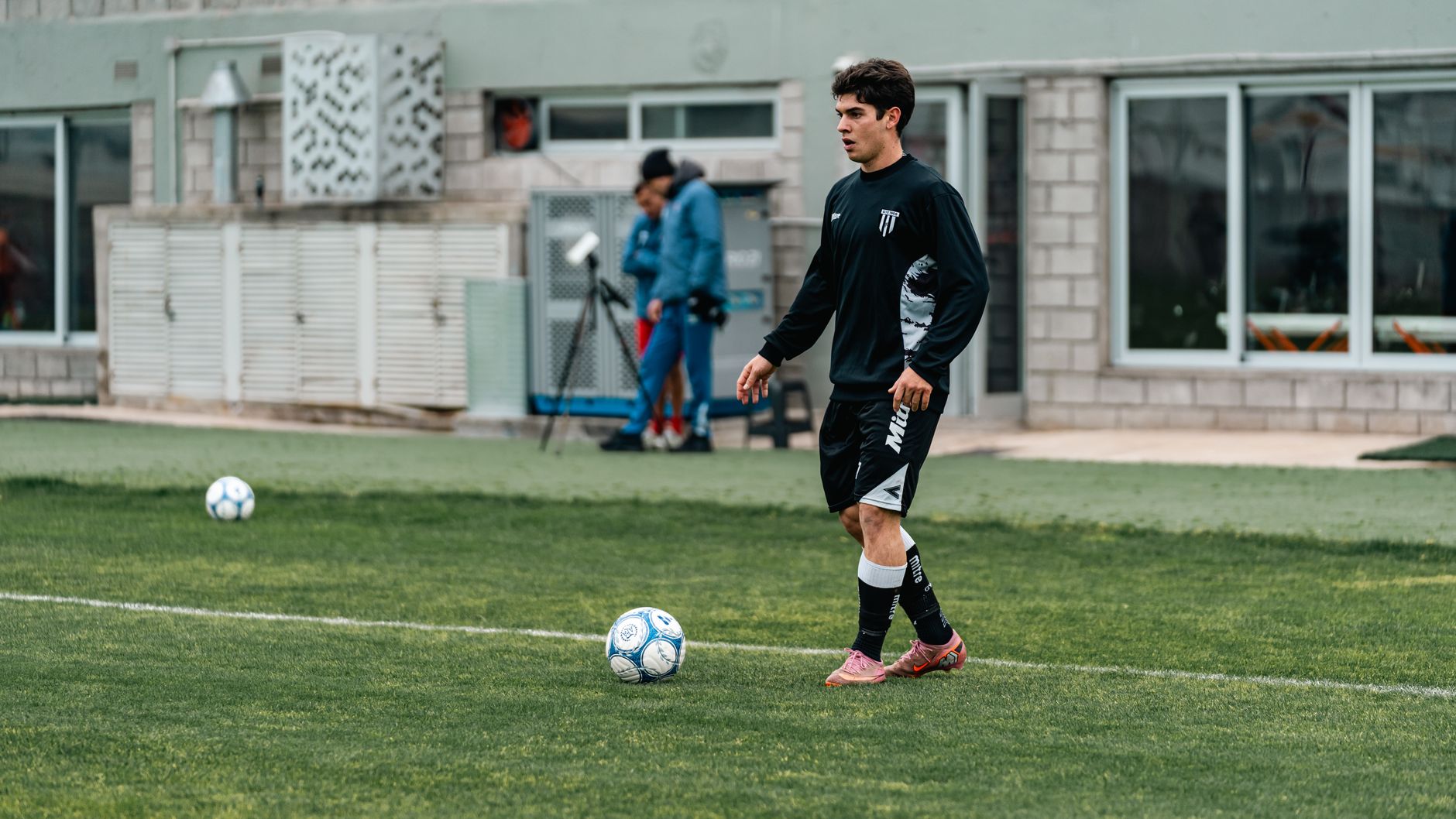 A young soccer player in training gear practices on a grassy field.