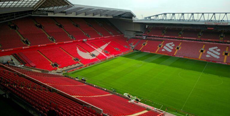 Aerial view of Anfield Stadium, Liverpool, showcasing its empty red seats and green pitch.