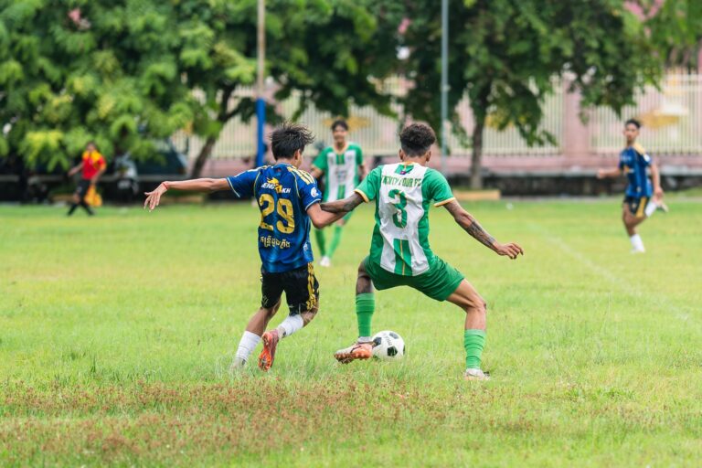 Soccer players in action on a lush green field during a daytime match.
