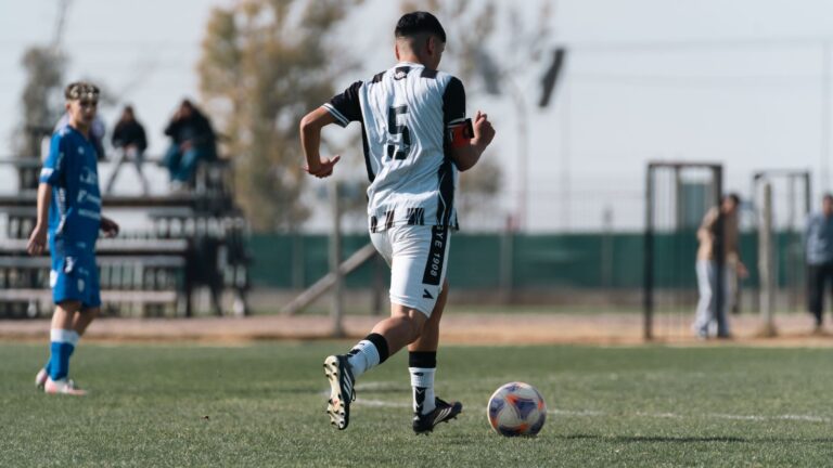 A soccer player dribbling on the field during a daytime match.