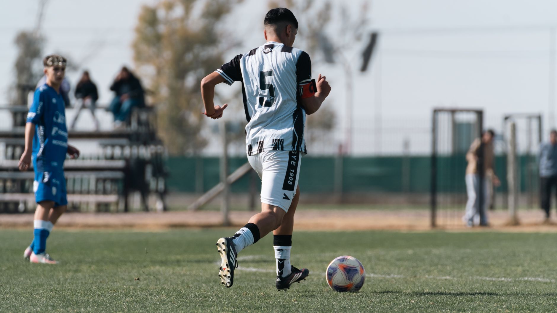 A soccer player dribbling on the field during a daytime match.