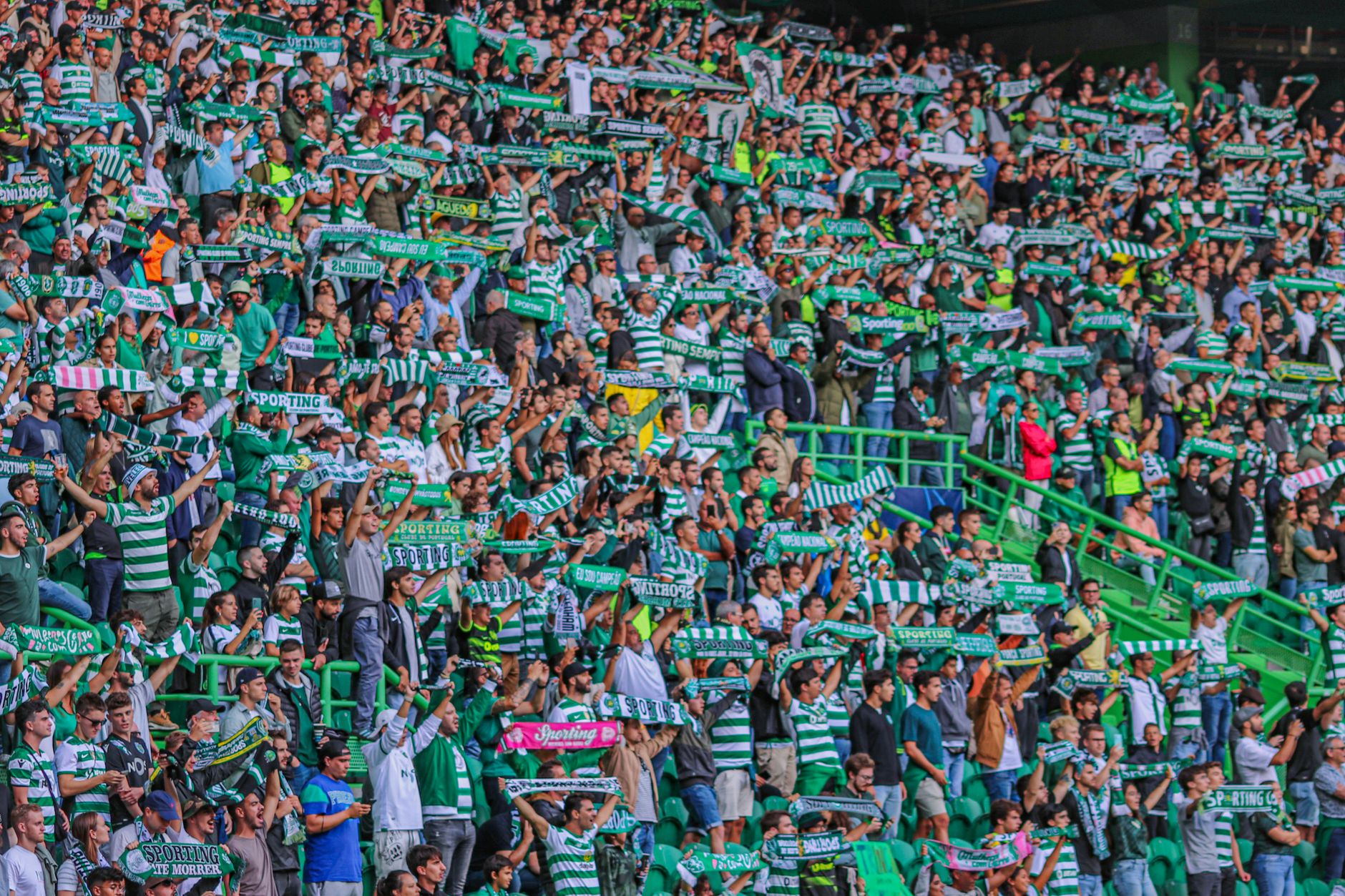Energetic crowd of soccer fans cheering with scarves at a stadium in Lisbon, Portugal.