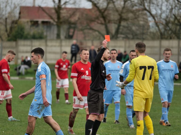 A heated moment as a referee shows a red card to a goalkeeper during a competitive soccer match.