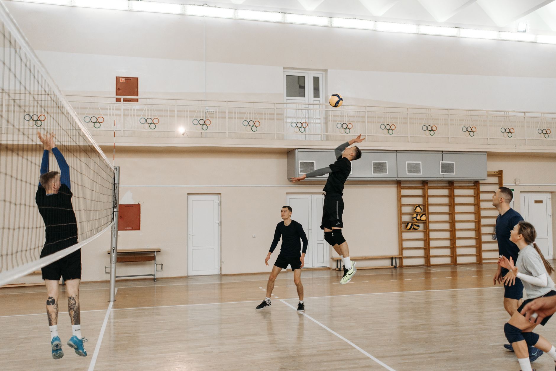 Competitive indoor volleyball match with athletes spiking the ball over the net.