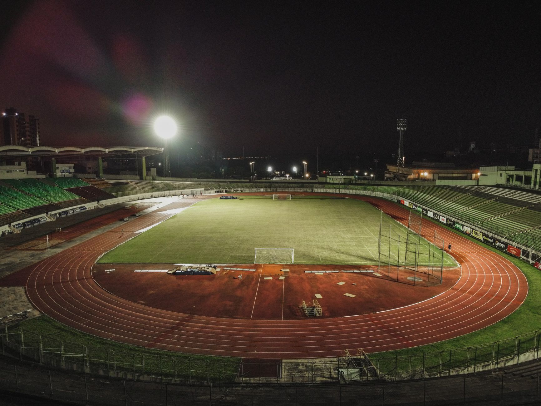 A captivating nighttime aerial view of Estádio Willie Davids in Brazil, showcasing its illuminated field and track.