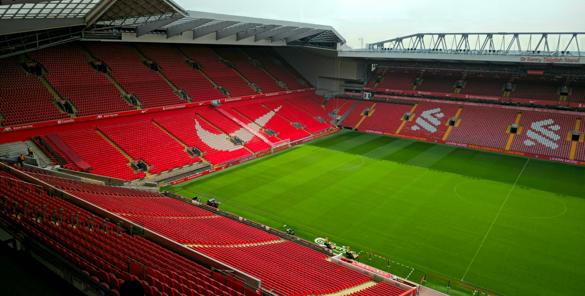 Aerial view of Anfield Stadium, Liverpool, showcasing its empty red seats and green pitch.