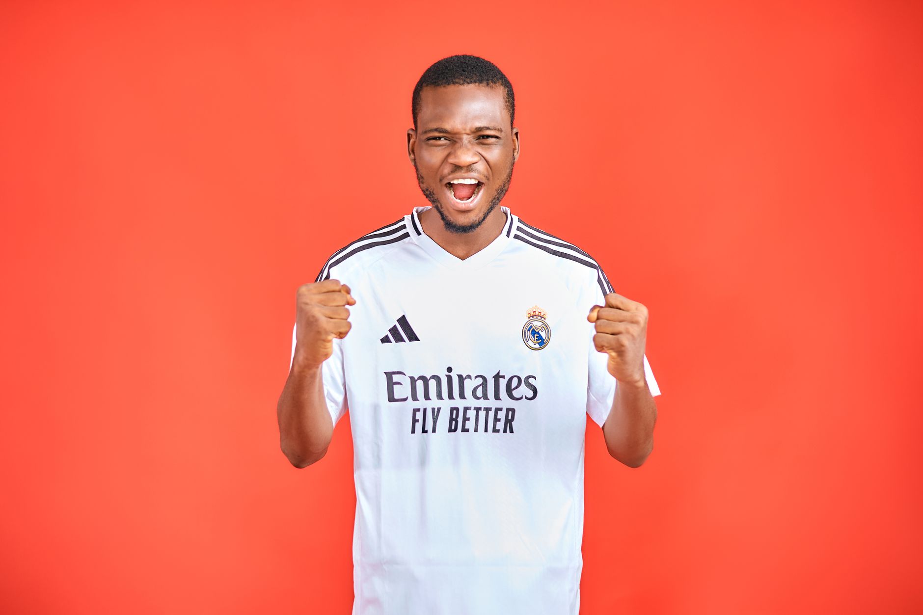 Energetic soccer fan in a team jersey cheering against a vibrant red background.