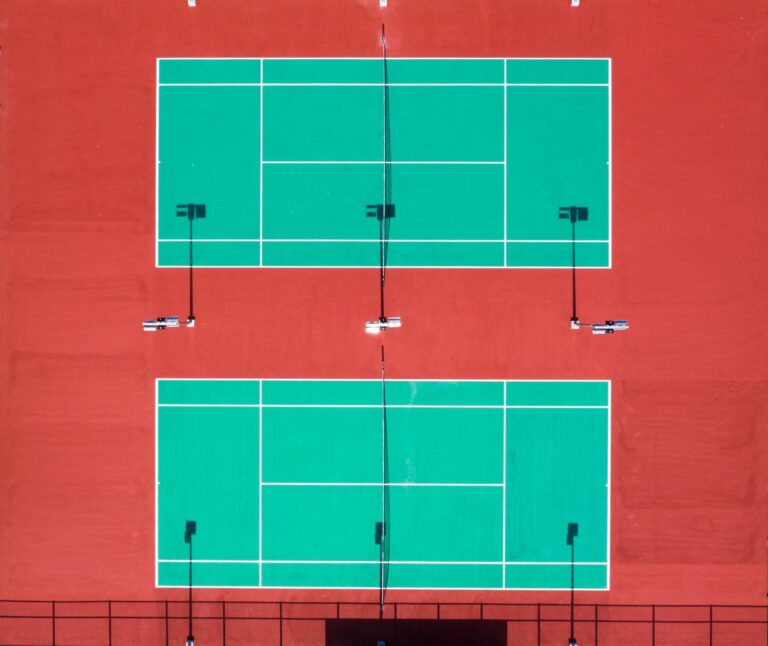 Bright aerial shot of two tennis courts on a sunny day.