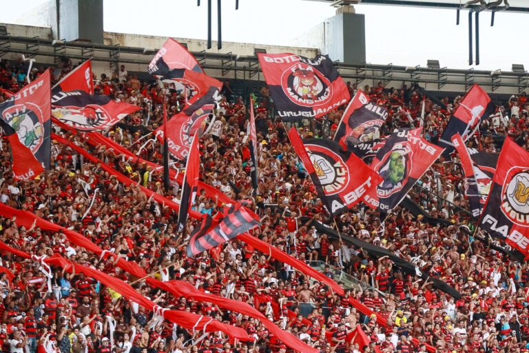 A lively crowd of Flamengo supporters waving flags at Maracanã Stadium in Rio de Janeiro.