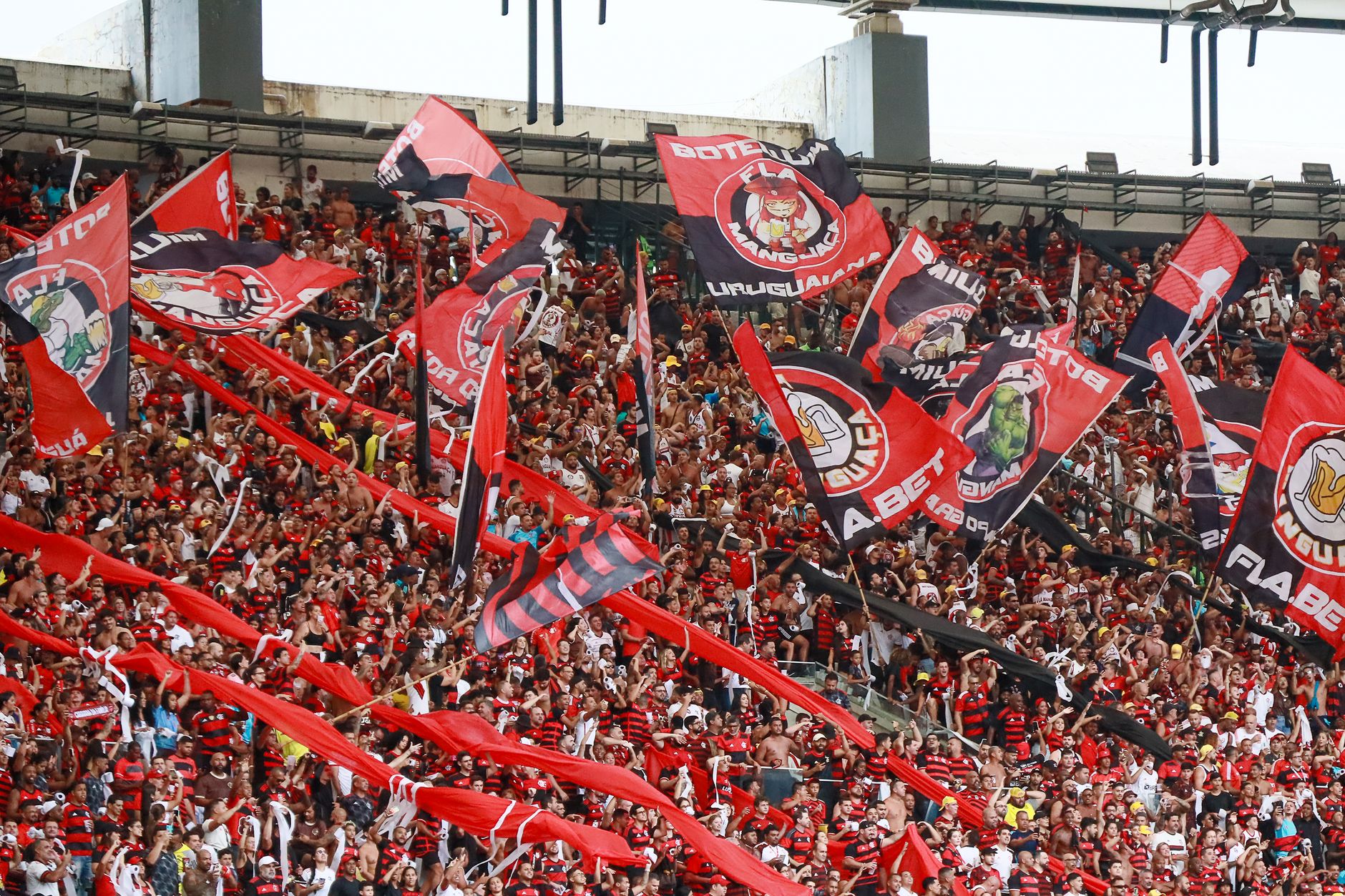 A lively crowd of Flamengo supporters waving flags at Maracanã Stadium in Rio de Janeiro.