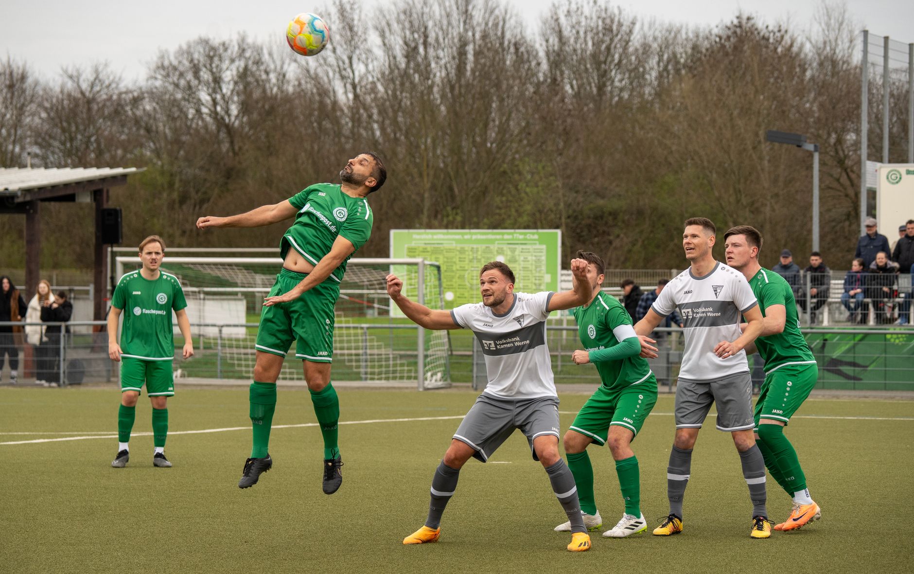 Dynamic action shot of adult men playing soccer outdoors, illustrating teamwork and athleticism.
