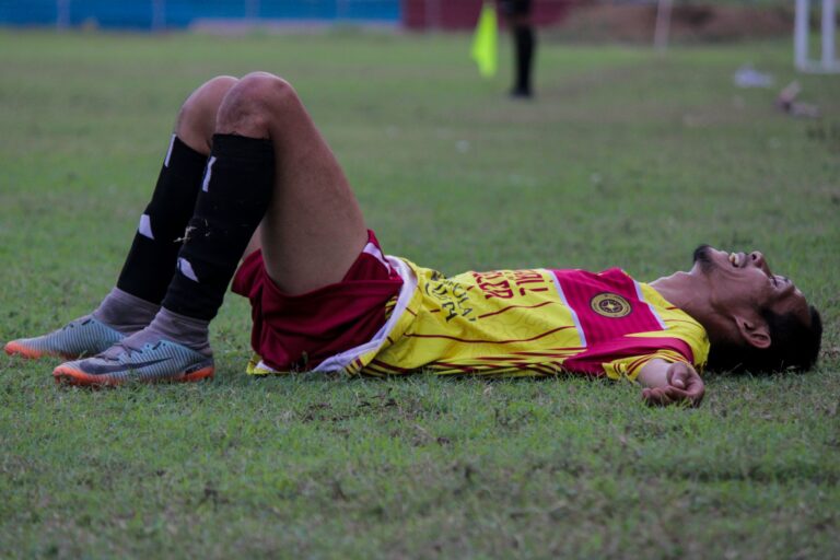 A tired soccer player lies on the grass field after an intense match.