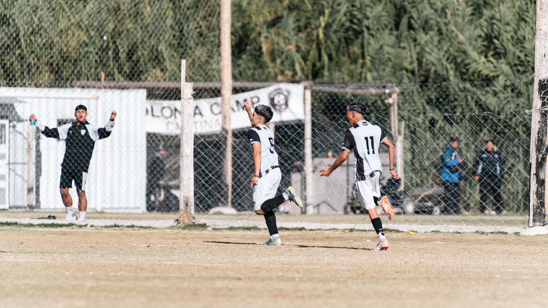Exciting moment of teenage soccer players celebrating a goal at an outdoor field.