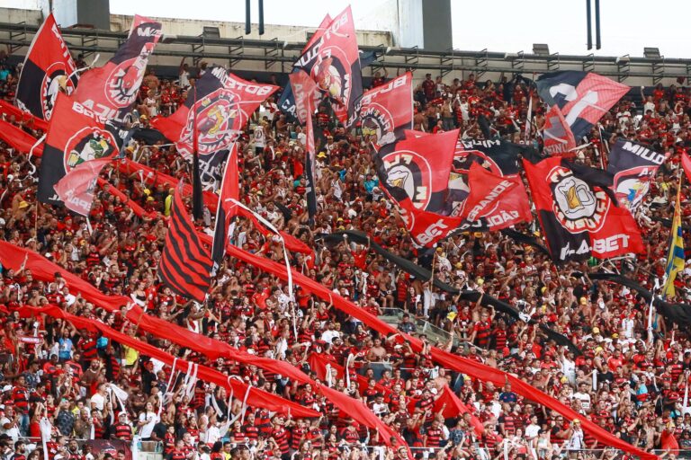 Fans passionately cheer with flags at a football match in Maracanã Stadium, Rio de Janeiro.