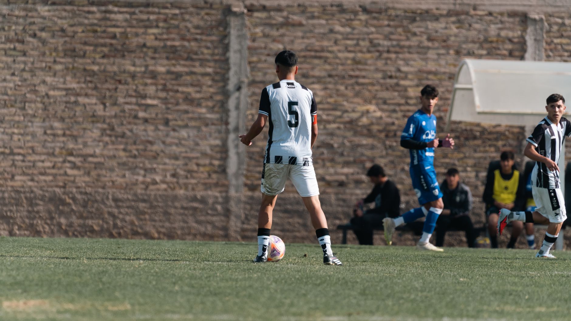 Teenage soccer player in action on the field, wearing number 5 jersey outdoors.