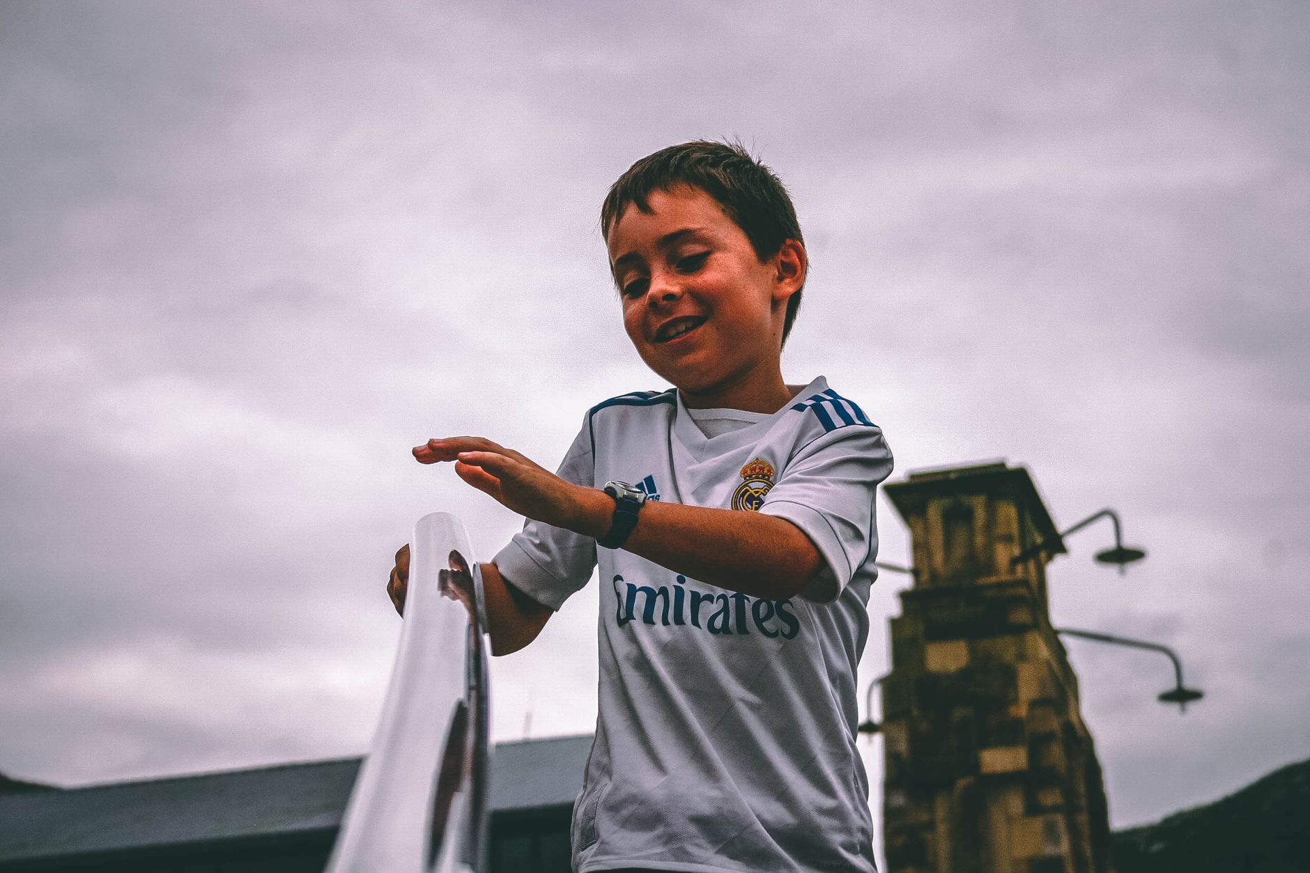 Cheerful young boy having fun outdoors on a cloudy day.