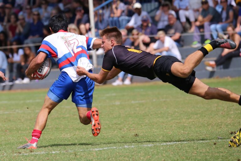 A thrilling rugby match capturing a player making a diving tackle on the field.