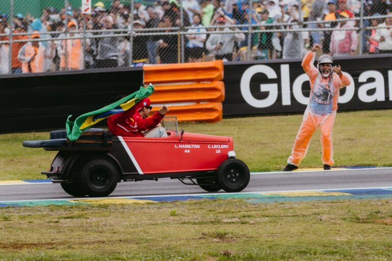 Joyful celebration at Formula 1 event in Interlagos, featuring a driver in a red buggy with a Brazilian flag.
