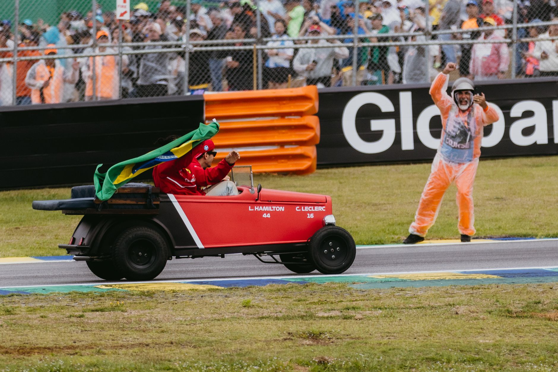 Joyful celebration at Formula 1 event in Interlagos, featuring a driver in a red buggy with a Brazilian flag.