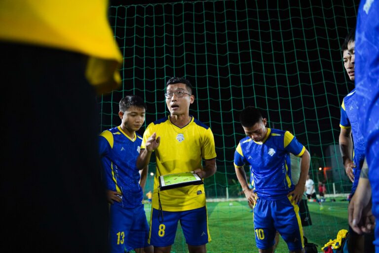 Soccer coach giving strategy talk to players on a night field.