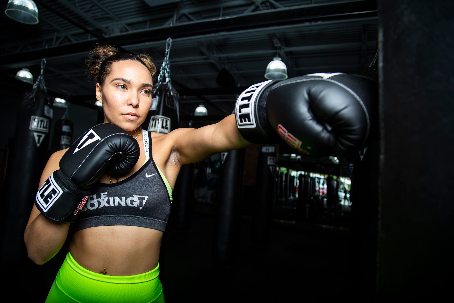 A focused female boxer in action during a training session wearing boxing gloves and sportswear.