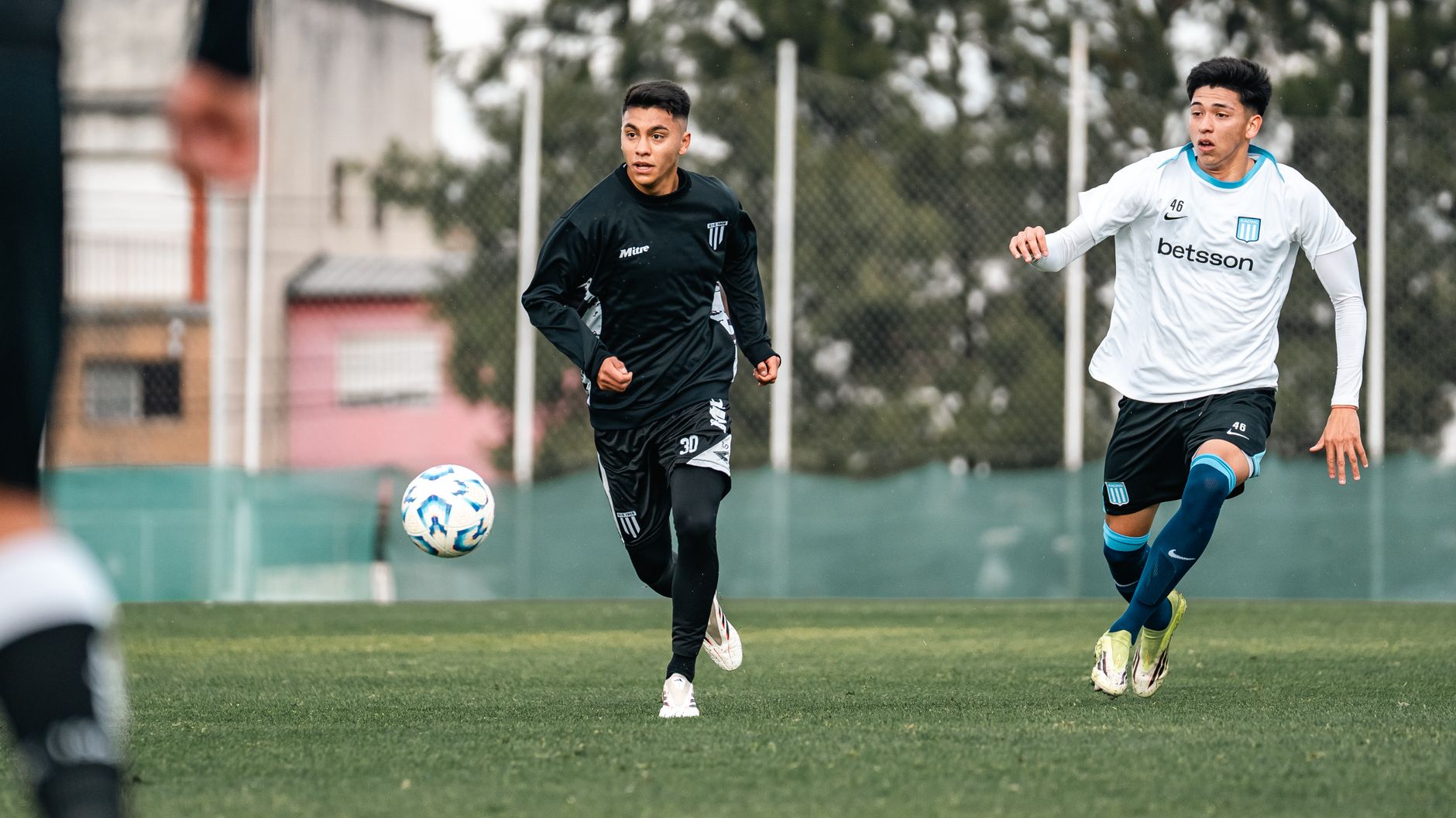 Two young soccer players competing fiercely on a grassy field during an outdoor match.