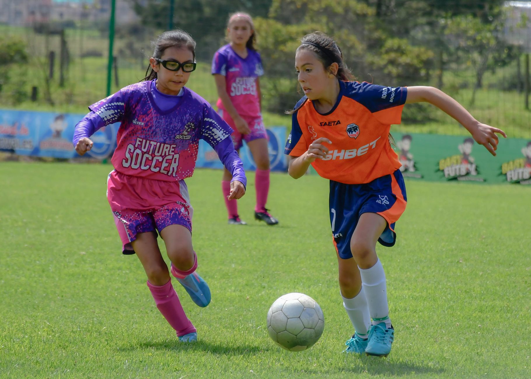 Teenage girls competing in an energetic soccer match on a sunny day, showcasing teamwork and sportsmanship.