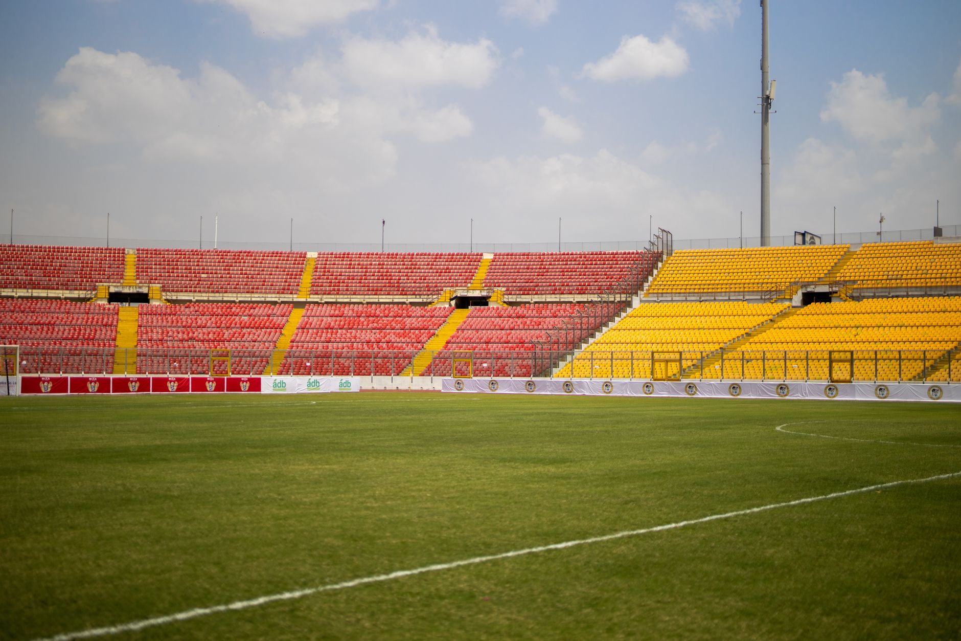 A sunny view of the empty seats and lush grass at Baba Yara Sports Stadium in Kumasi, Ghana.