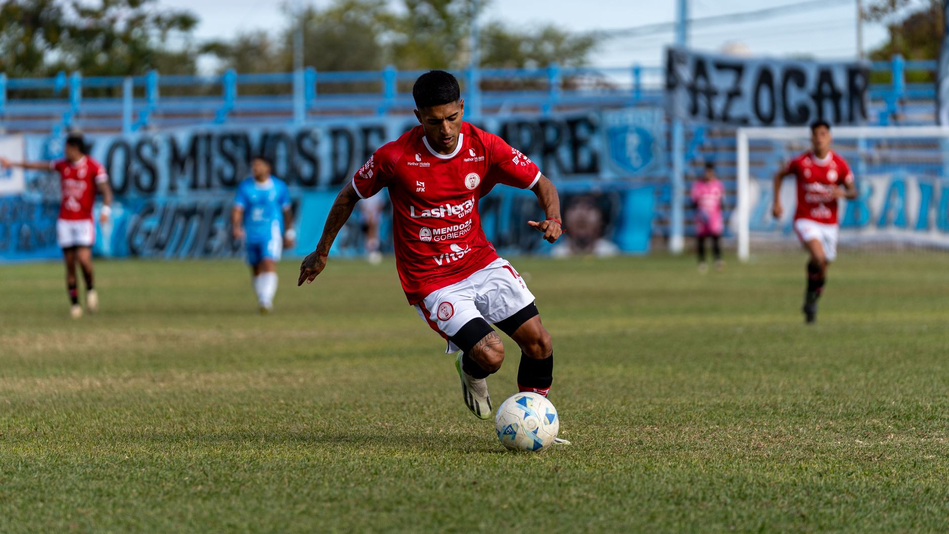 A soccer player in red jersey skillfully dribbling the ball during a match outdoors.