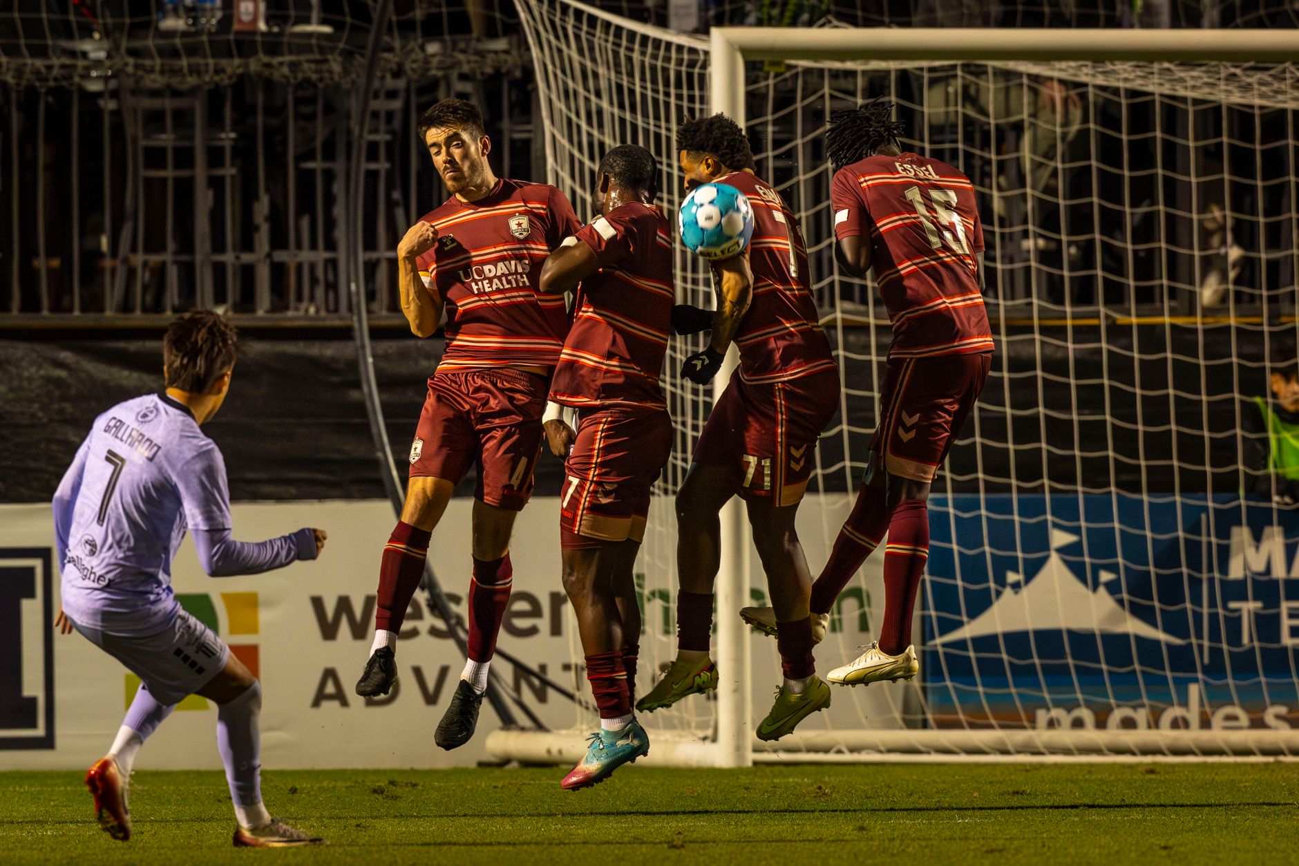 Intense soccer moment capturing a team's defensive wall blocking a free kick.