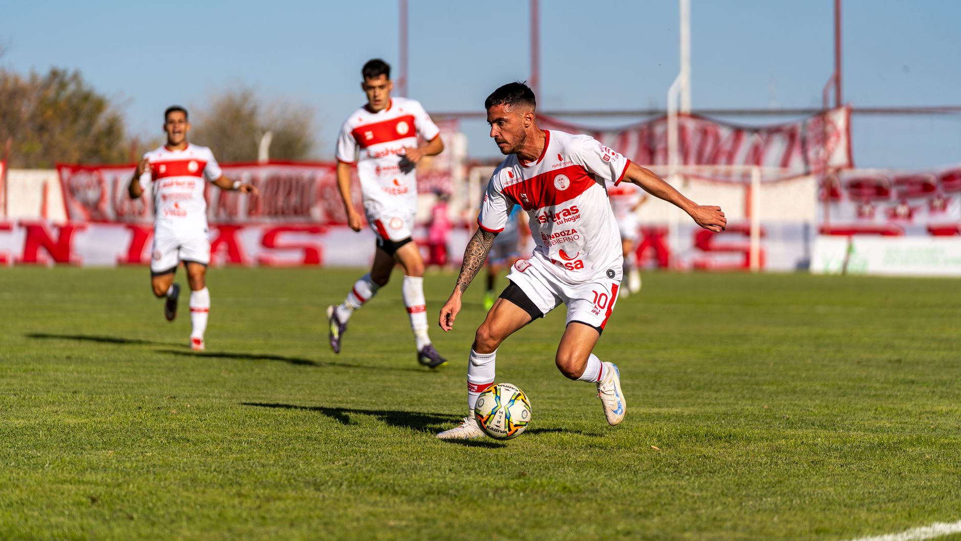 Players engaged in a competitive soccer match outdoors on a sunny day.