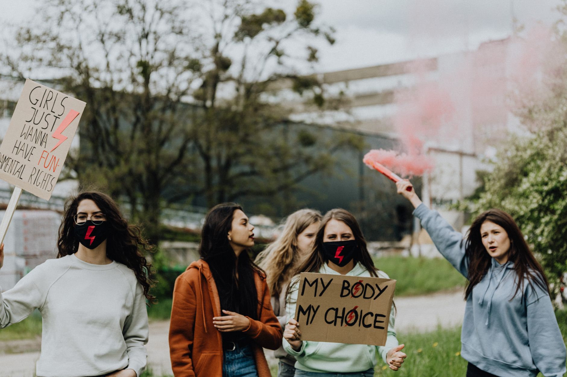 A group of women protesting outdoors with placards and colored smoke for feminist rights.