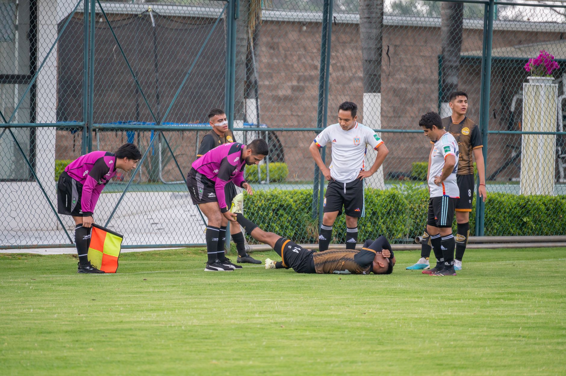 Soccer player injured on the field with teammates and referee assistance in Texcoco, Mexico.
