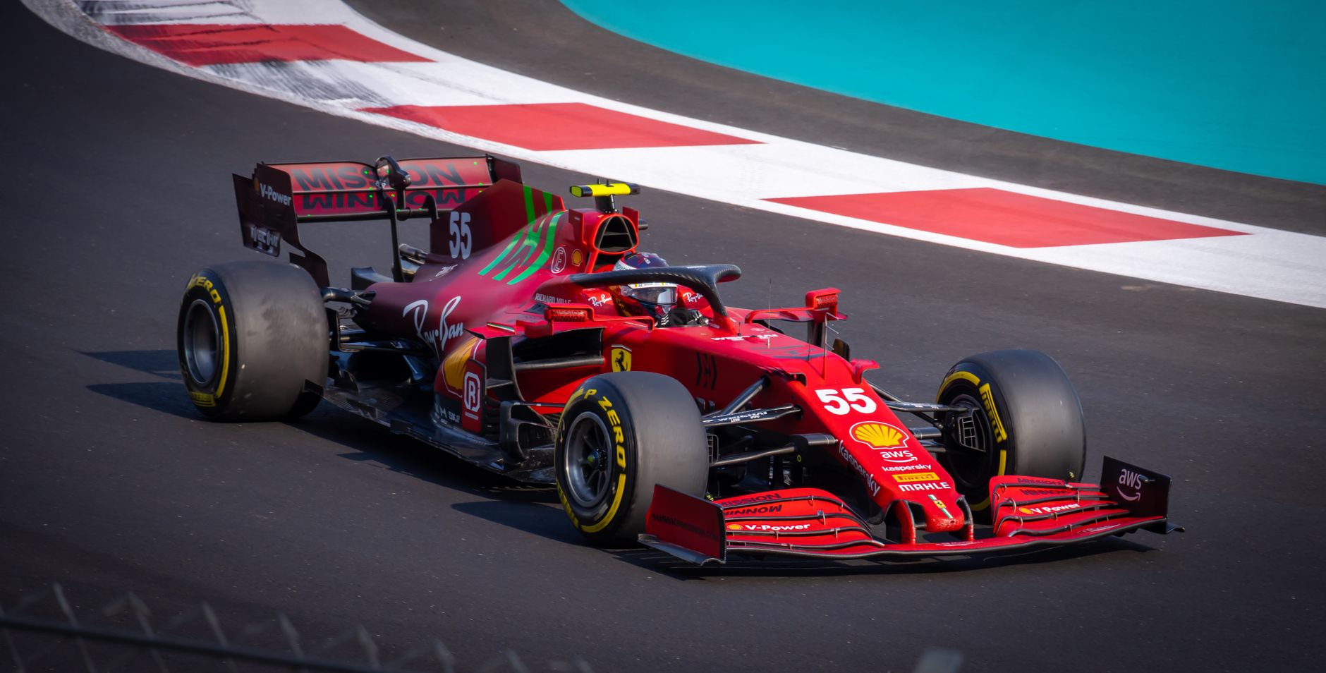 Red racing car speeding on an asphalt circuit, showcasing dynamic motion and precision.