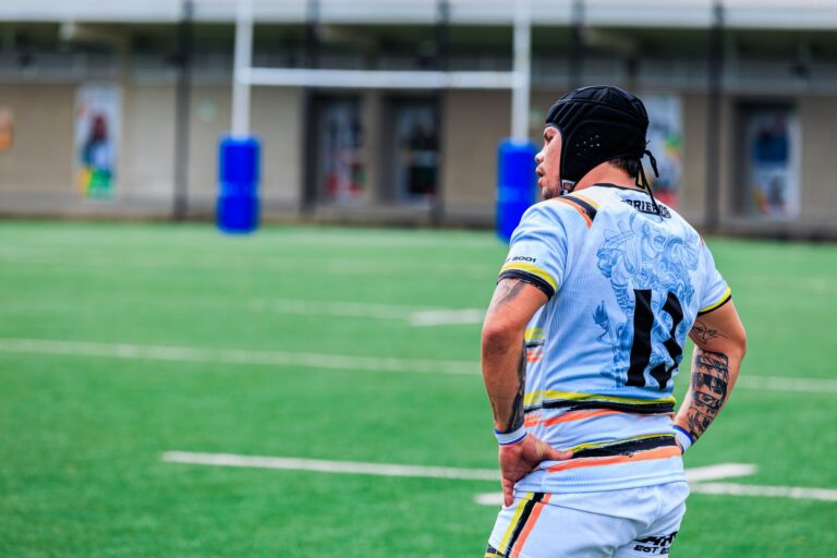 Rugby player standing on field, focused and ready for action, in colorful uniform.