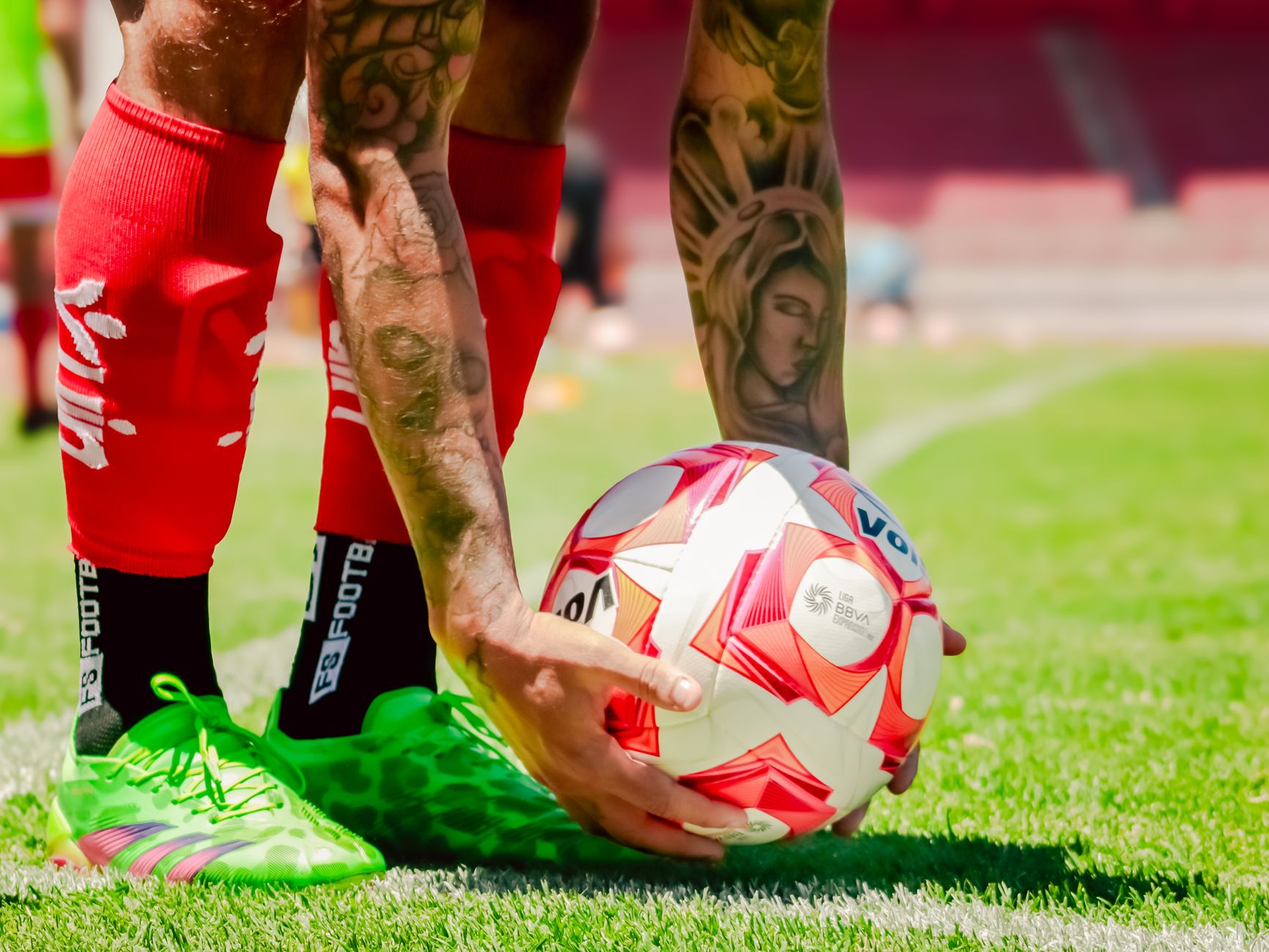 Close-up of a soccer player's tattooed arms placing the ball for a free kick.