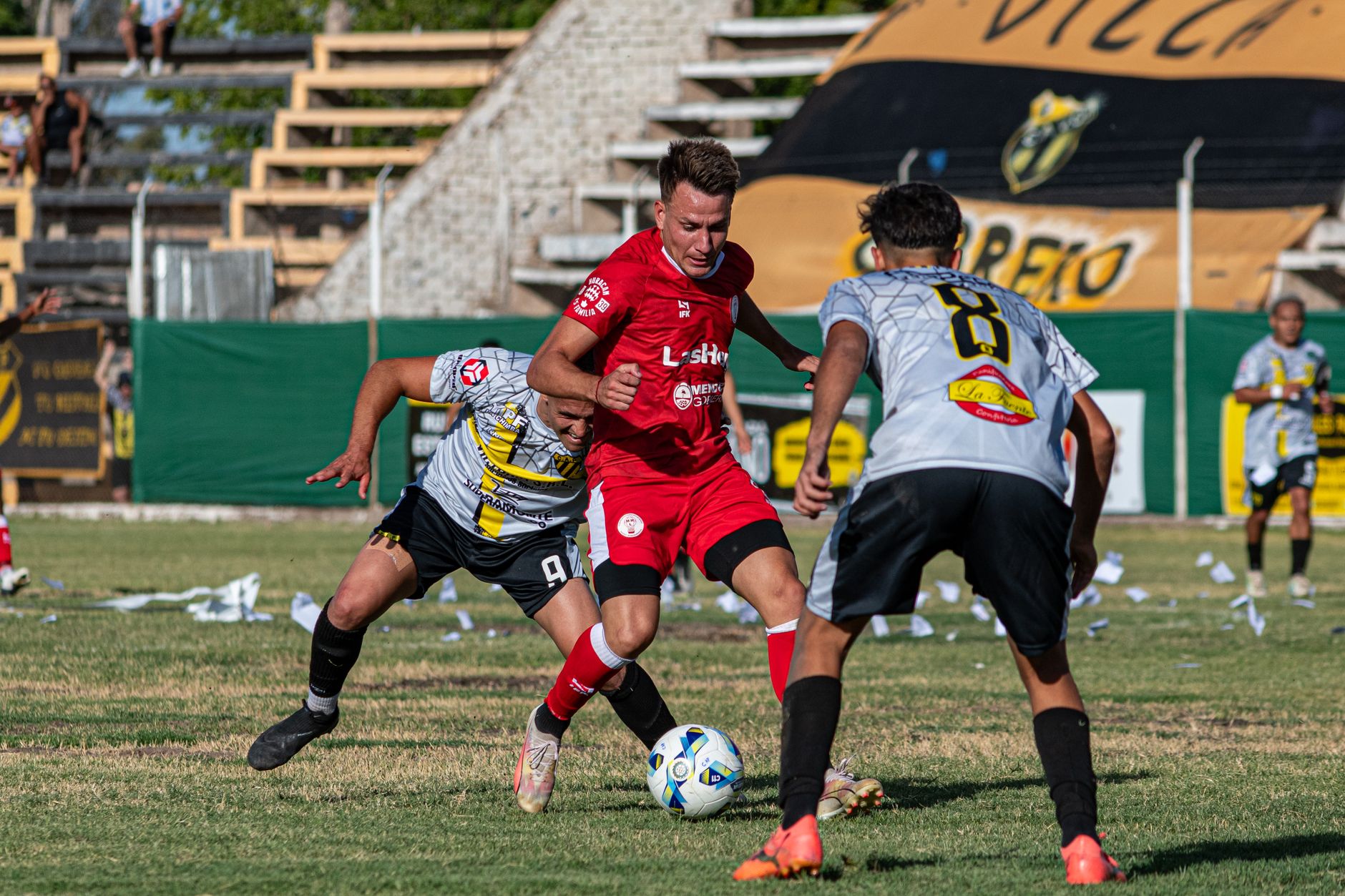 Three male soccer players competing intensely on a grassy field.