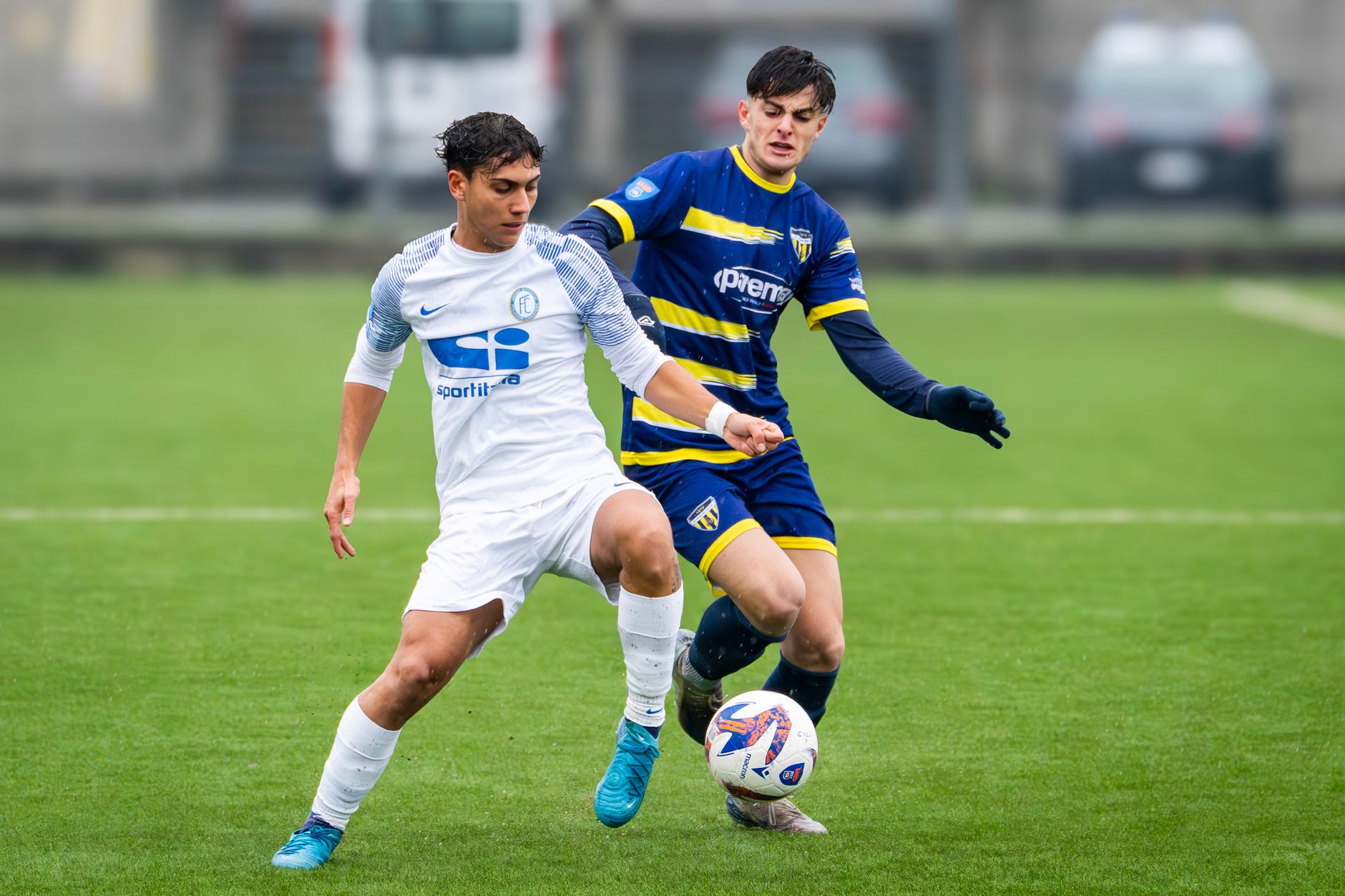 Two young male soccer players in action during an outdoor soccer match, displaying skill and competition.